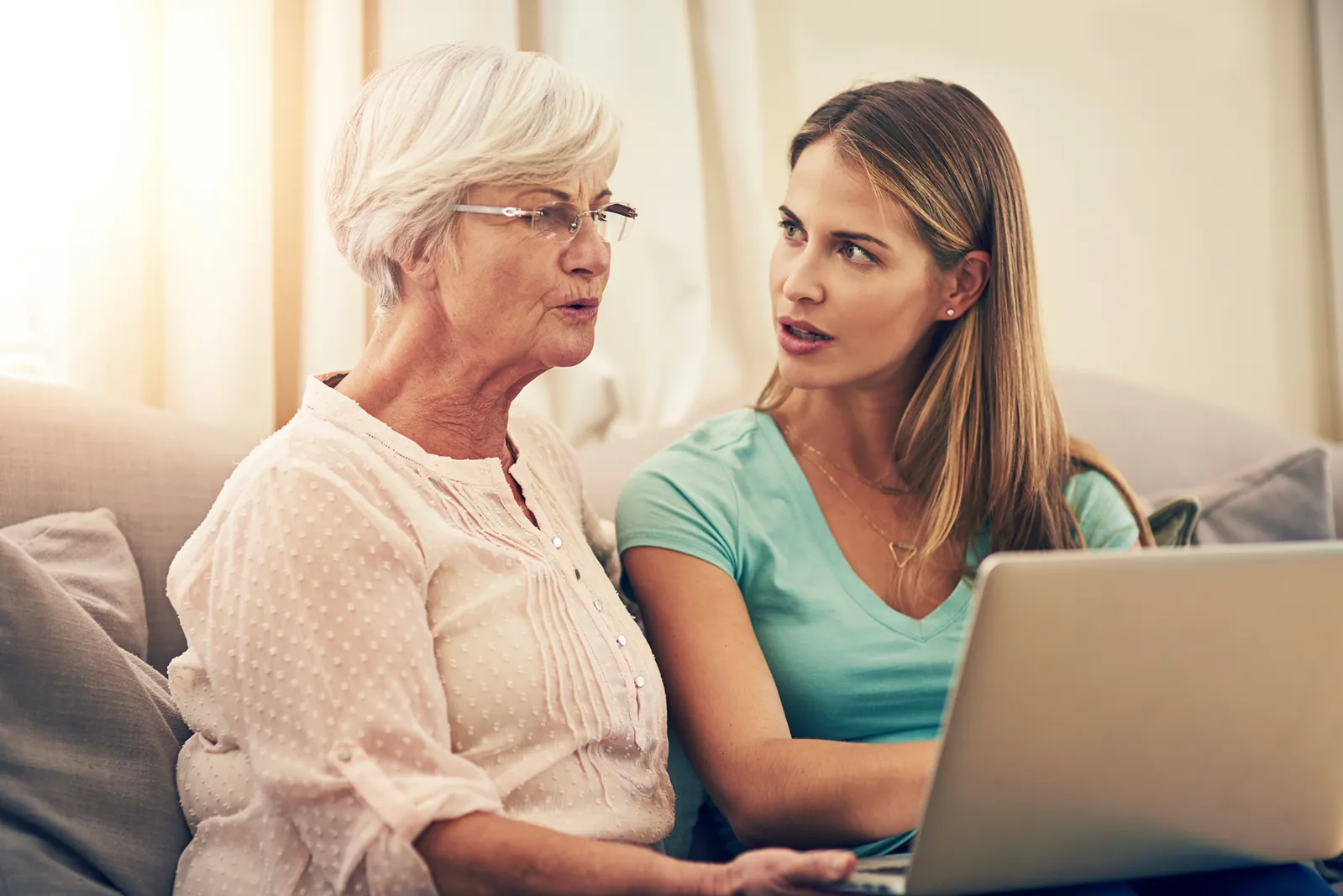 Tochter unterstützt Seniorin bei der Online-Suche am Laptop zu Hause